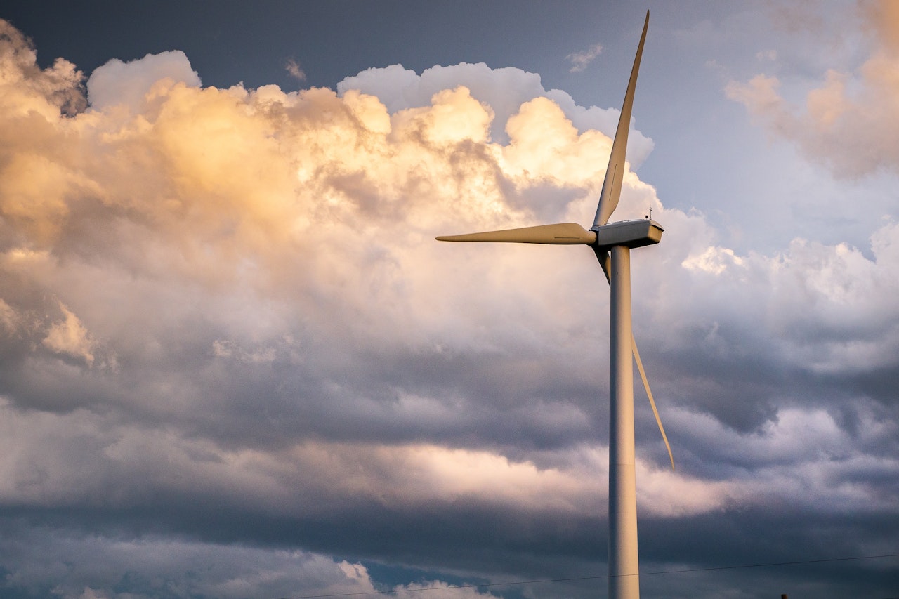 The photo depicts a wind turbine set against a stormy Oklahoma sky.