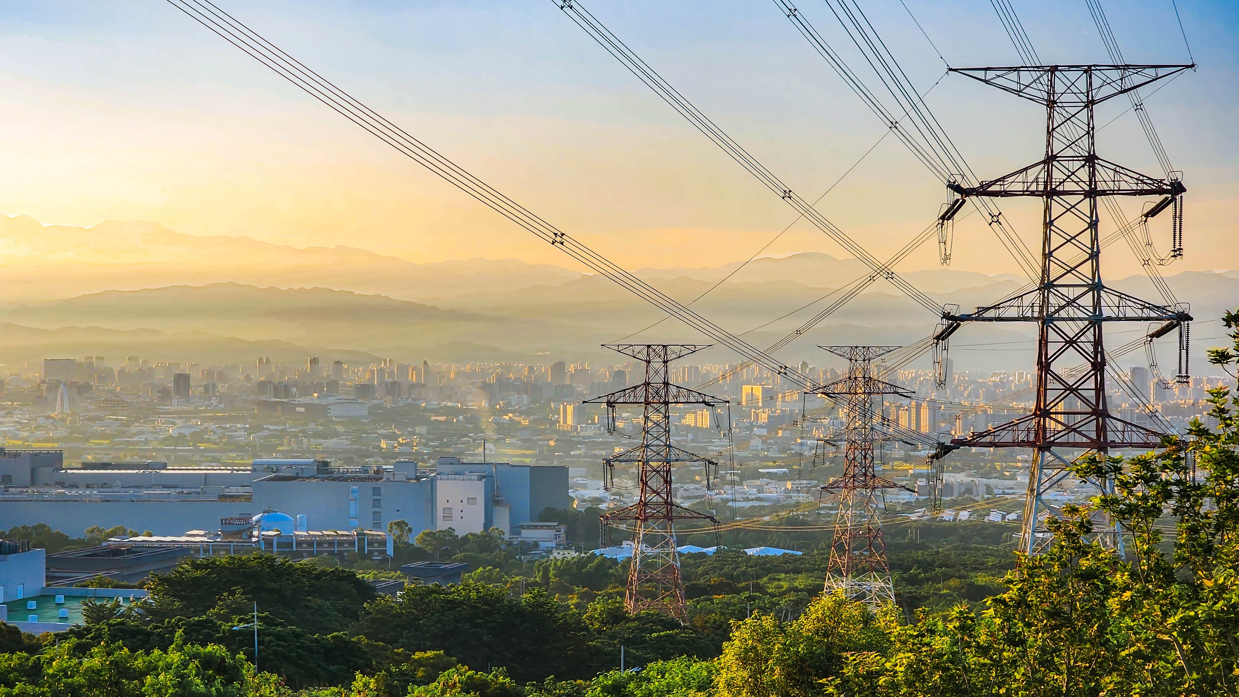 The photo depicts a View of power poles and lines with buildings and mountains in background shutterstock 2325254401