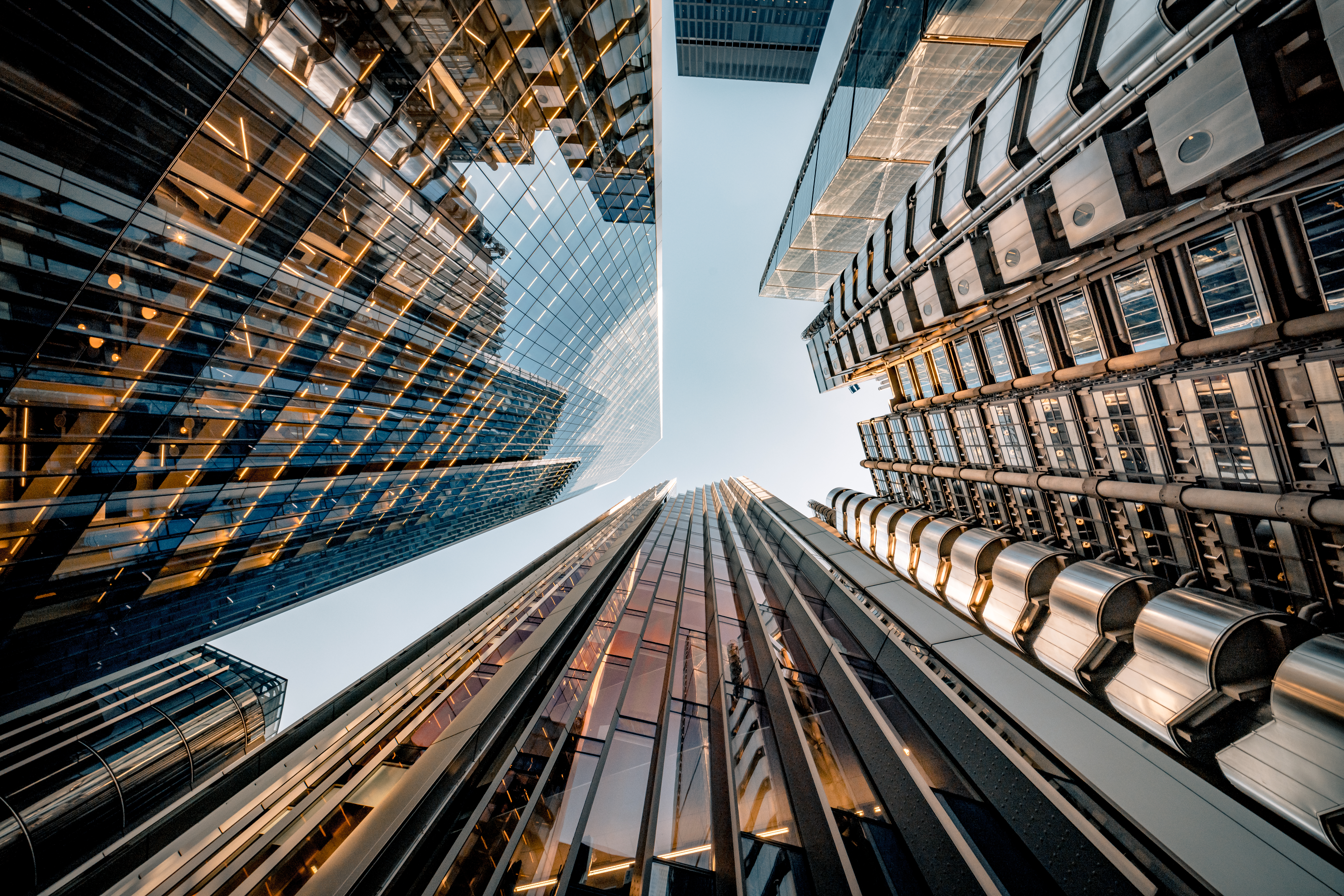 Photo depicts Highly detailed abstract wide angle view up towards the sky in the financial district of London City and its ultra modern contemporary buildings with unique architecture on a cloudy day