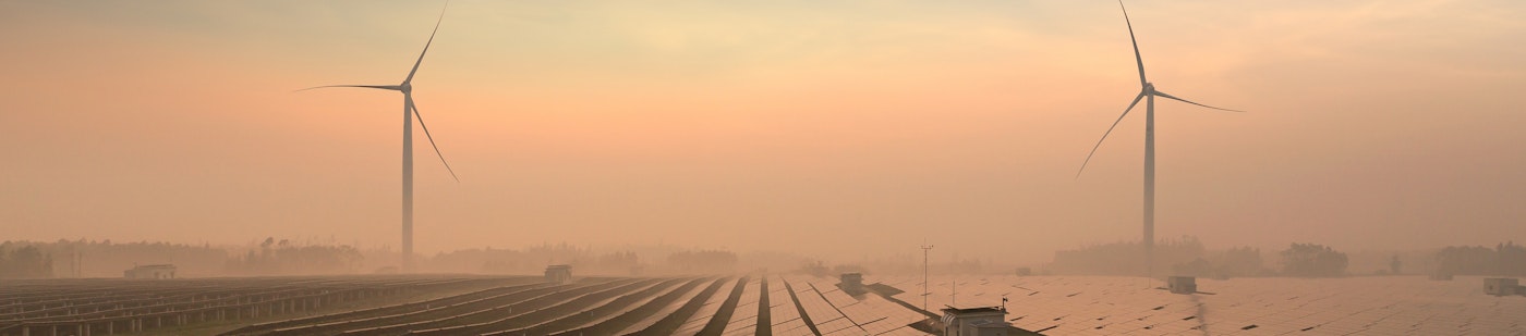 Photo depicts a solar panels and windmills in the power plant