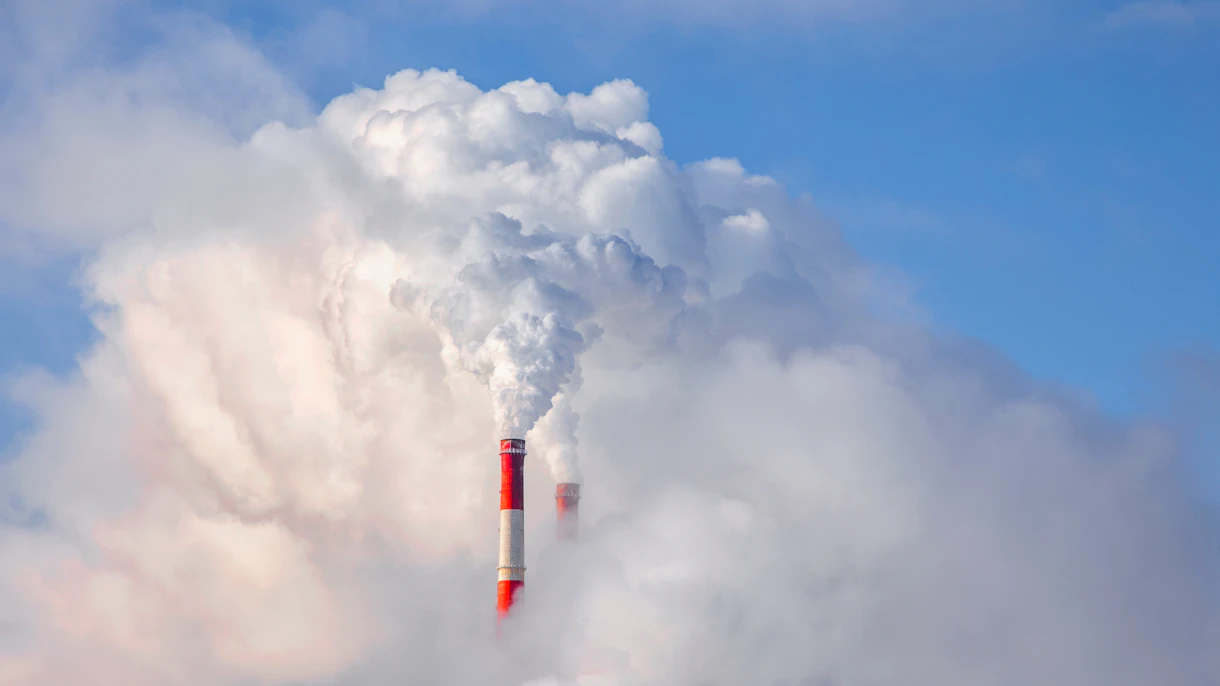Foto que muestra el humo de las chimeneas contra el fondo del cielo azul Shutterstock 1662983170
