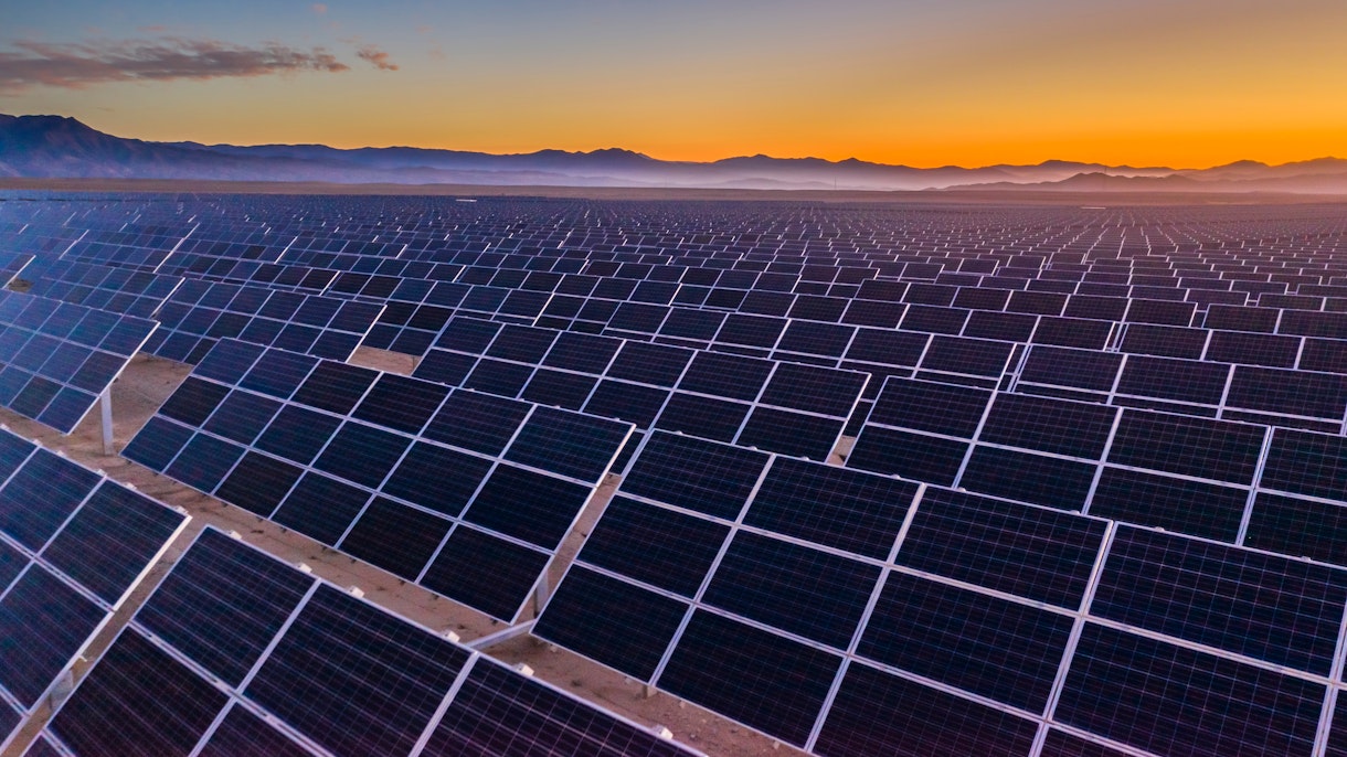 照片描繪了智利阿塔卡馬沙漠旱地上數百排太陽能板的鳥瞰圖。 日落時從空中無人機的角度來看，沙漠中部的巨大光伏電站