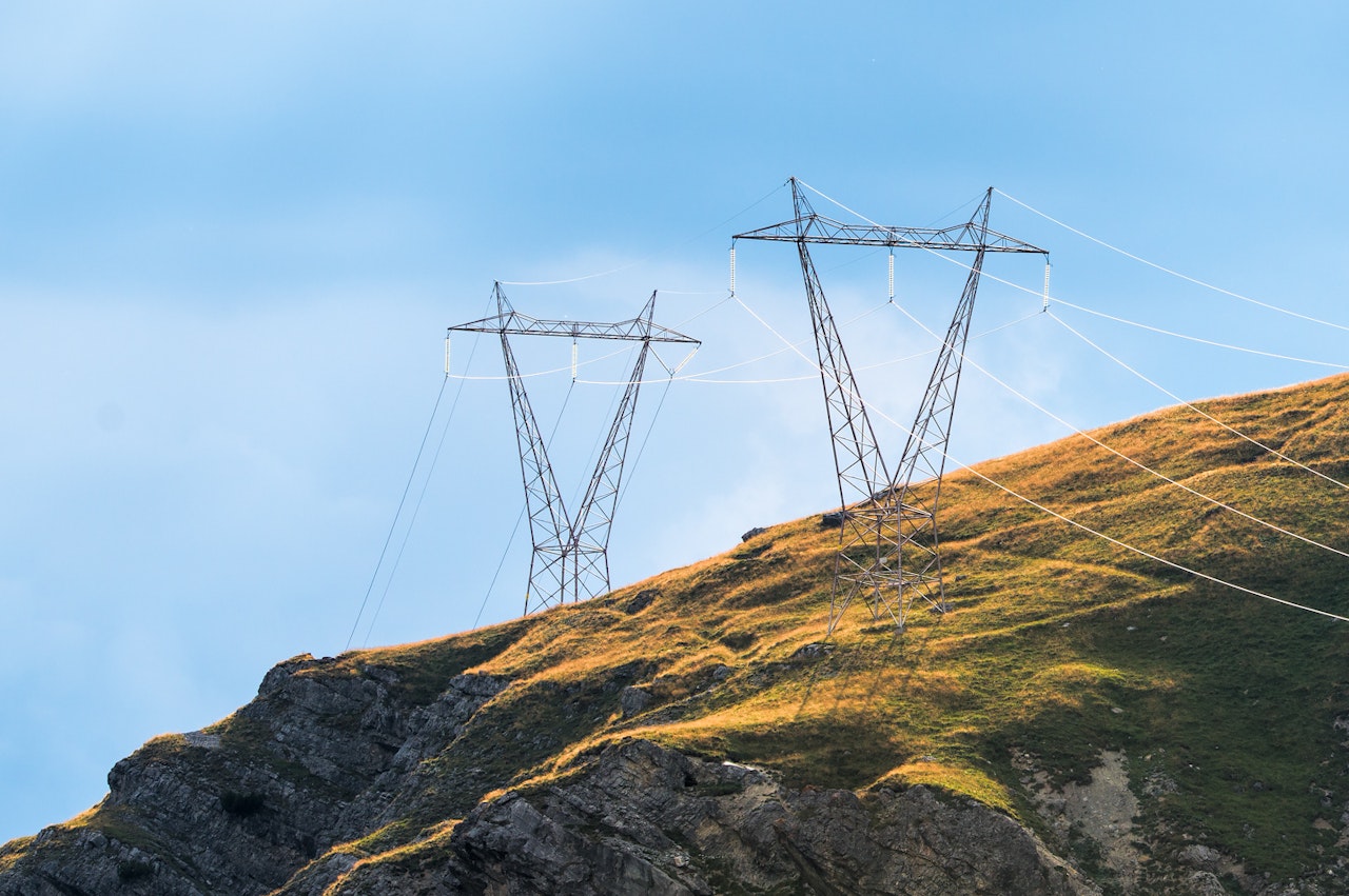 Photo depicts power pylons in the mountains