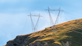 Photo depicts power pylons in the mountains