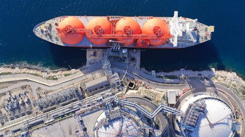 Photo shows an aerial view of a LNG barge in water at the port of a gas facility