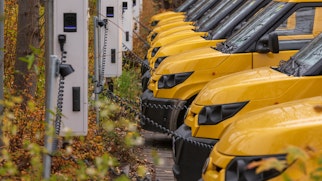Photo shows a line of yellow electric cars plugged in to charging points