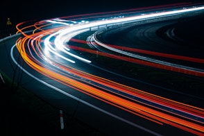 Cover of Transitioning India's Road Transport Sector - A photo of a dark abstract background with bands of colored rays of light moving from the center