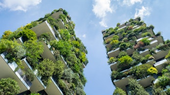 Photo of a modern and ecological skyscraper with many trees on each balcony