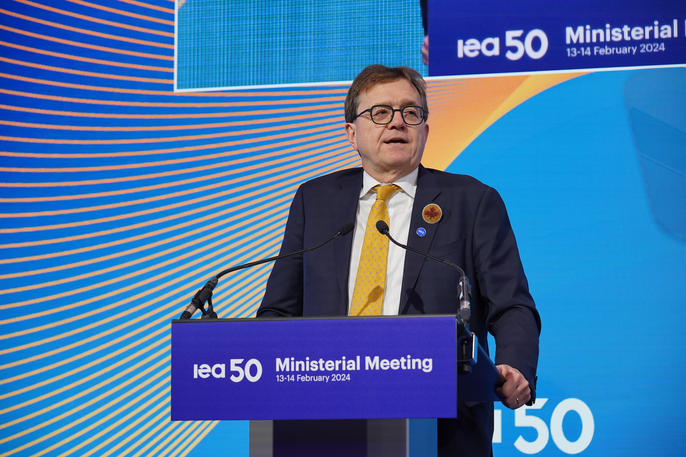 Photo shows candian energy minister on a stage at the podium.