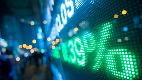 The photo depicts a display stock market numbers with defocused street lights background