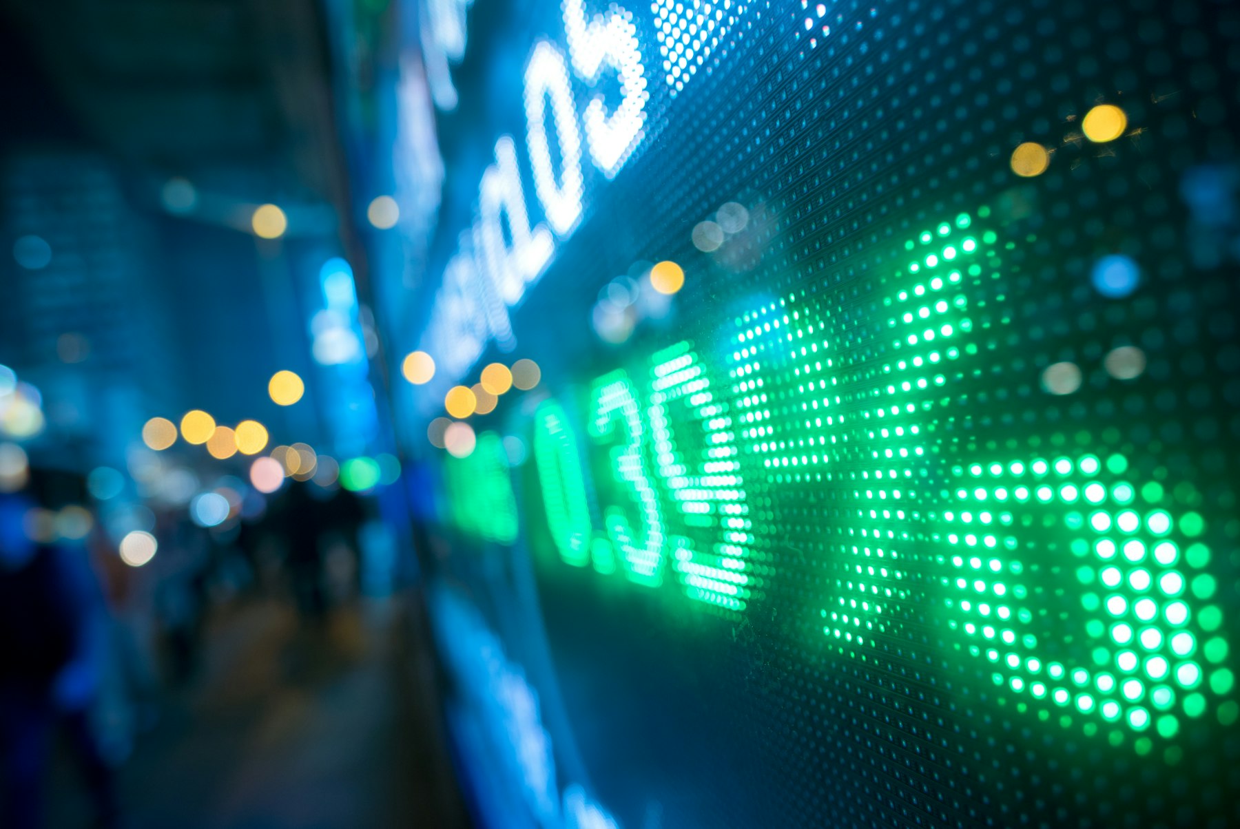 The photo depicts a display stock market numbers with defocused street lights background